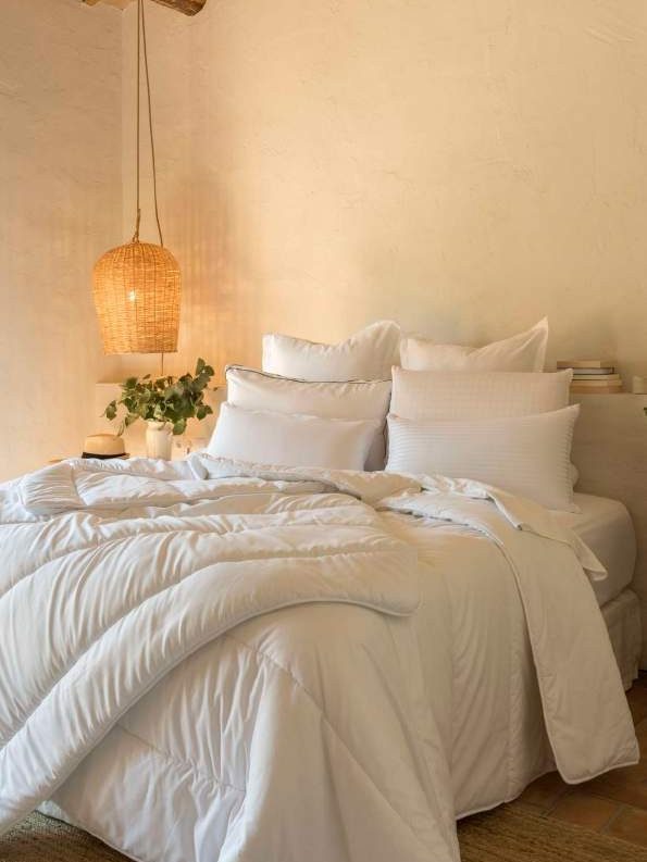 Cama vestida de blanco con edredón y luz cálida